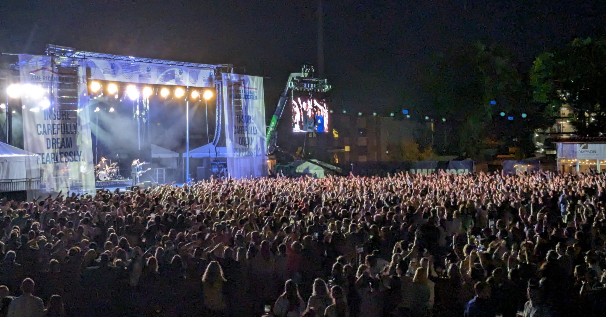 View of Train playing from the stage to a large crowd with hands raised.