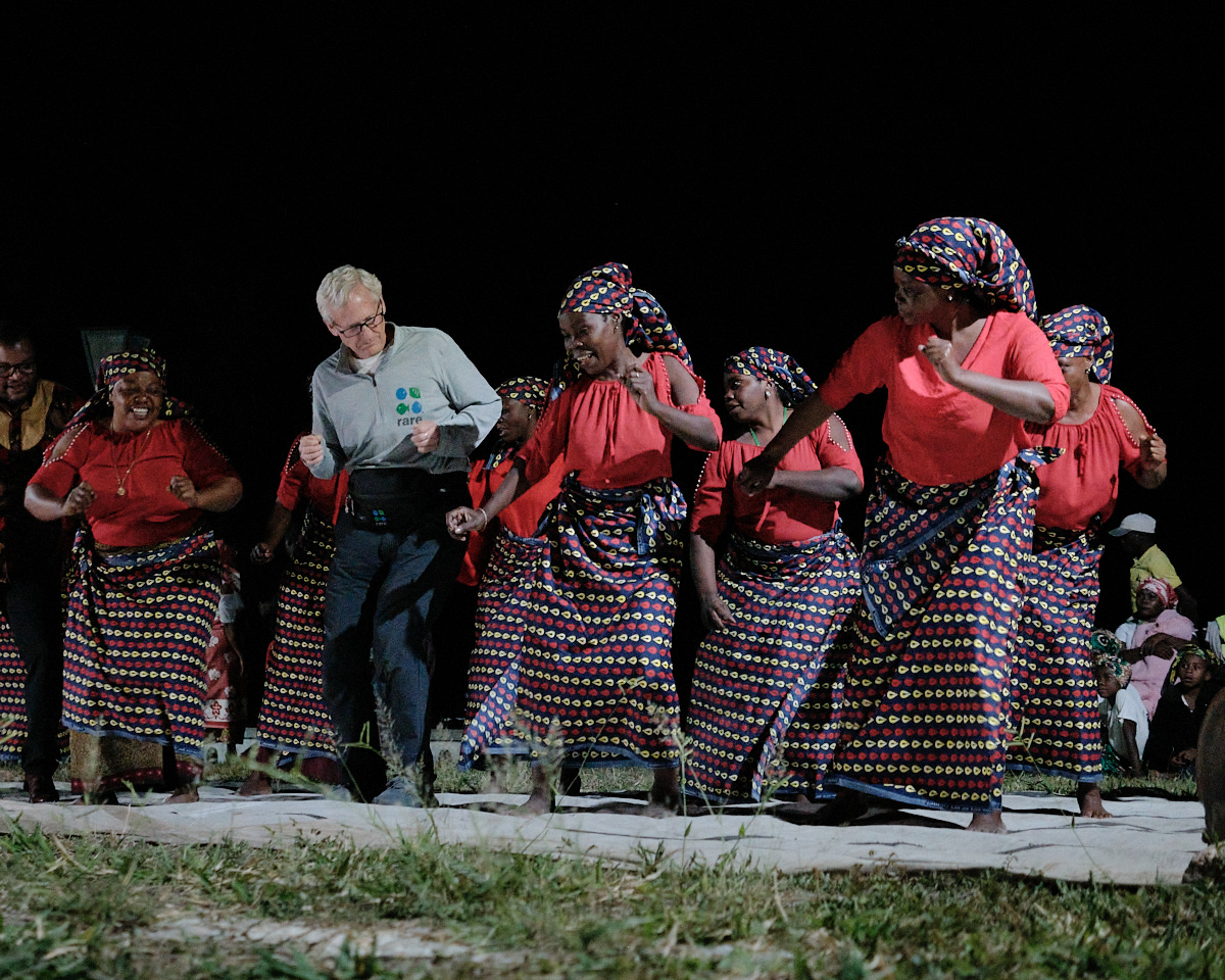 <# Rare’s chairman dancing with local women outside at night #>