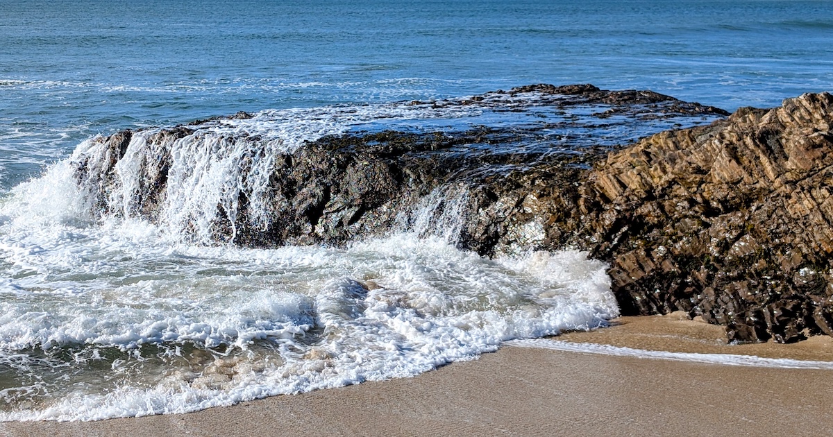 waves crashing over a rock in the ocean